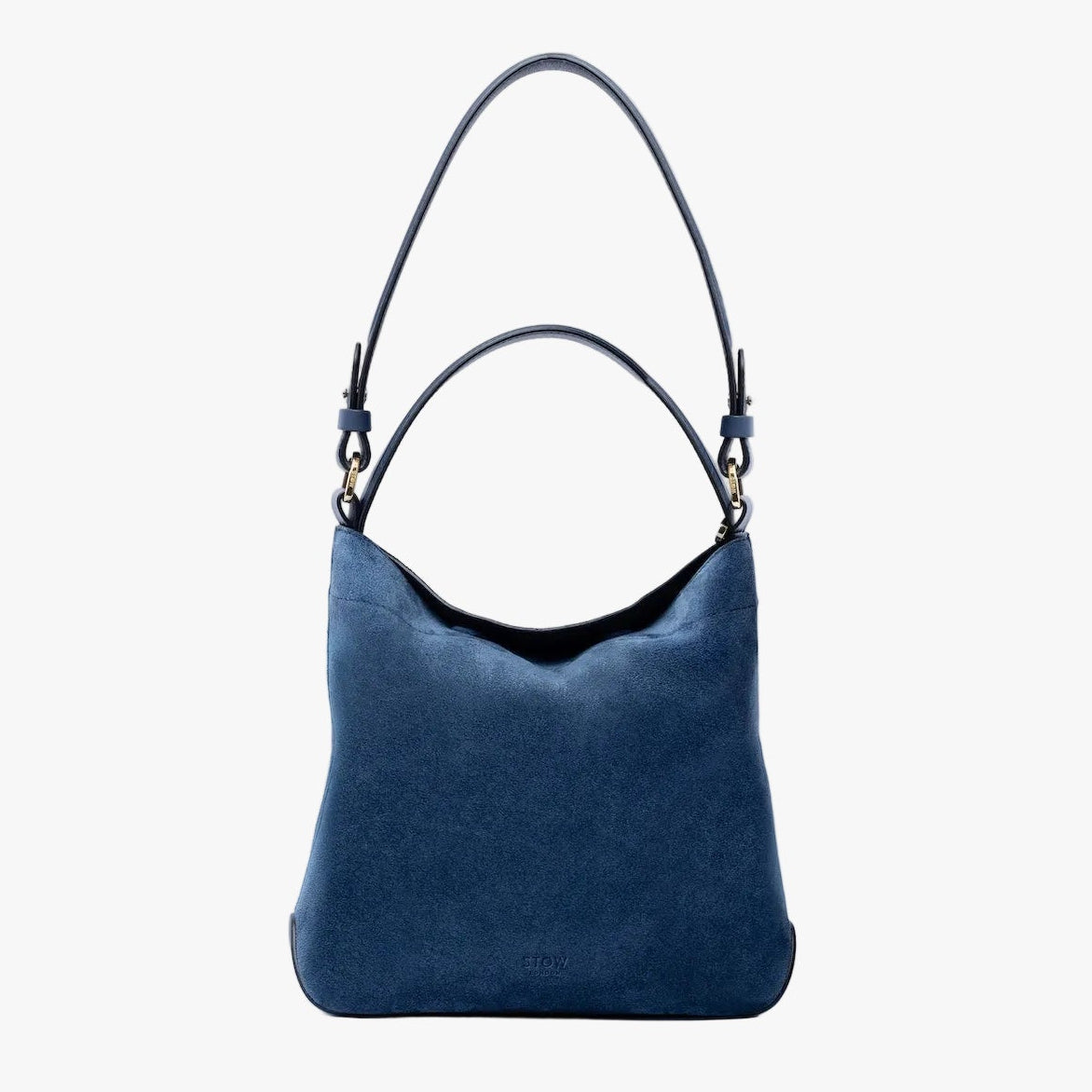 STOW London's Midi Curve in Navy suede leather on a light grey background featuring the detachable shoulder strap and top handle with gold hardware and details 