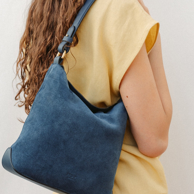 Model wearing STOW London's Midi Curve in Navy leather featuring the detachable shoulder strap with gold hardware