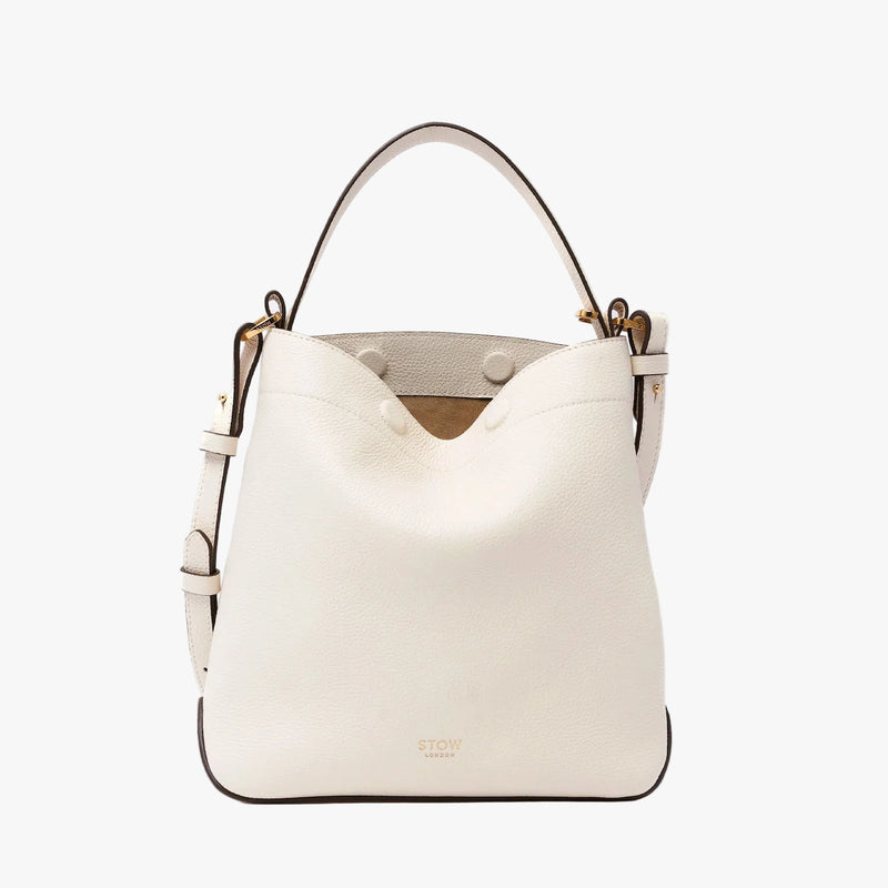 STOW London's Midi Curve in Spring Moon pebbled leather and detachable crossbody strap featuring gold-coated stainless steel hardware on a light grey background