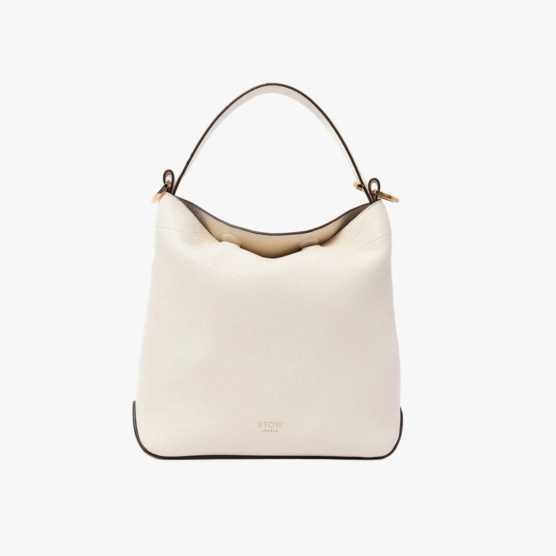 STOW London's Midi Curve in Spring Moon pebbled leather shaped as a flap bag featuring gold-coated stainless steel hardware on a light grey background