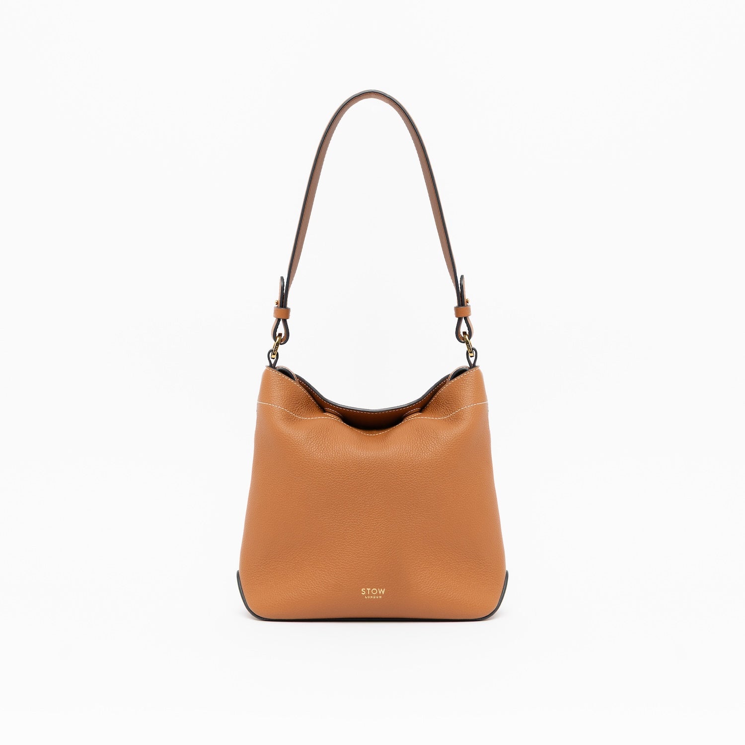 STOW London's Midi Curve in Earth Tan leather with the detachable shoulder strap on a light grey background featuring gold details 