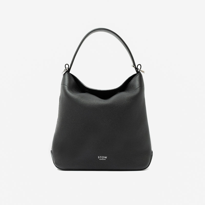 STOW London's Midi Curve in Black pebbled leather styled as a flap bag featuring silver stainless steel hardware on a light grey background
