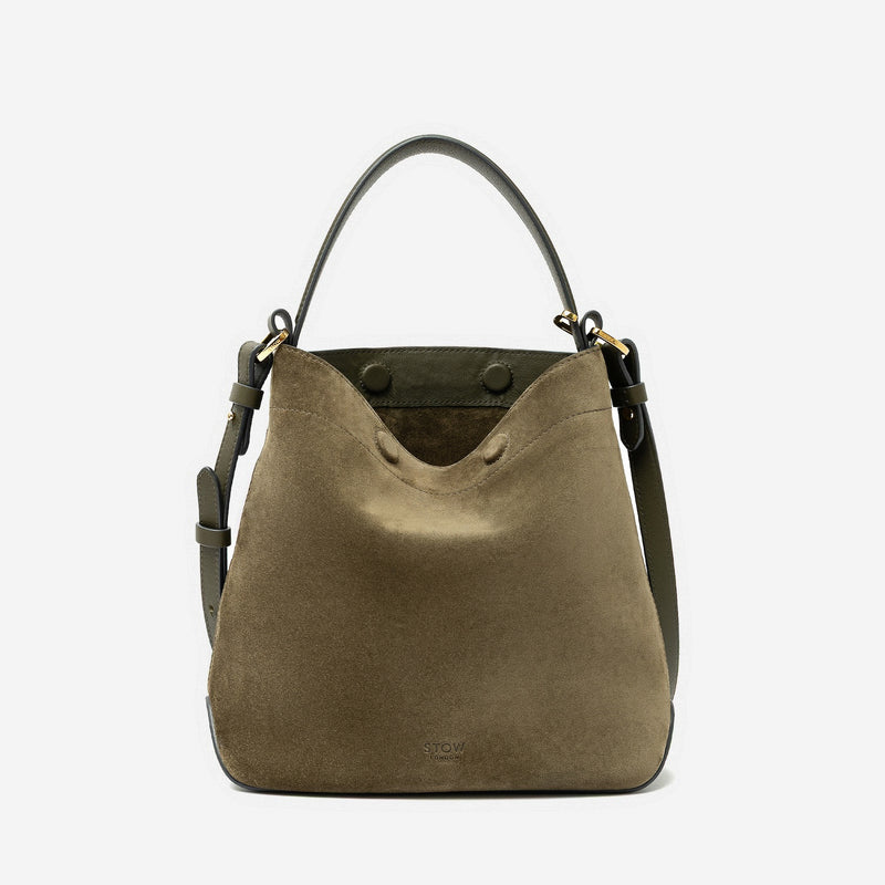 STOW London's Midi Curve in Dark Green suede leather and detachable crossbody strap featuring gold-coated stainless steel hardware on a light grey background