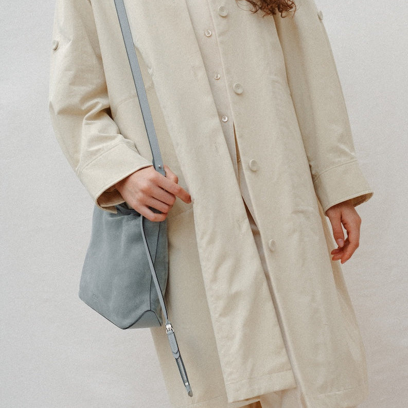 Model wearing STOW London's Midi Curve in Misty Blue suede leather on her shoulder featuring silver stainless steel hardware
