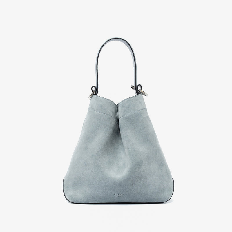 STOW London's Midi Curve in Misty Blue suede leather styled in a triangular shape featuring silver stainless steel hardware on a light grey background