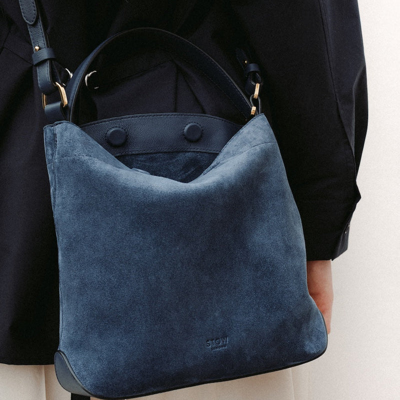 Close up of model wearing STOW London's Midi Curve in Navy suede leather crossbody featuring gold-coated stainless steel hardware