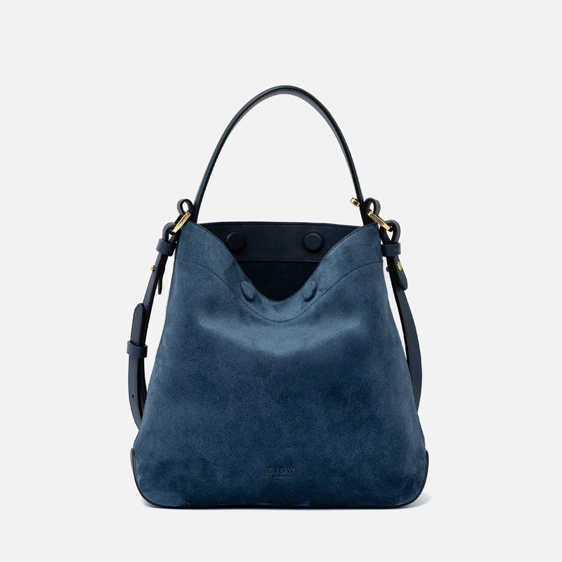 STOW London's Midi Curve in Navy suede leather featuring gold-coated stainless steel hardware on a light grey background