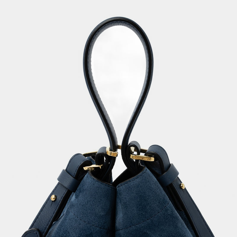 Close up of the handle on STOW London's Midi Curve in Navy suede leather featuring gold-coated stainless steel hardware, clip and detachable crossbody strap on a light grey background