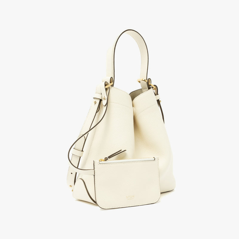 STOW London's Midi Curve in Spring Moon pebbled leather with its matching, detachable interior pouch featuring gold-coated stainless steel hardware on a light grey background