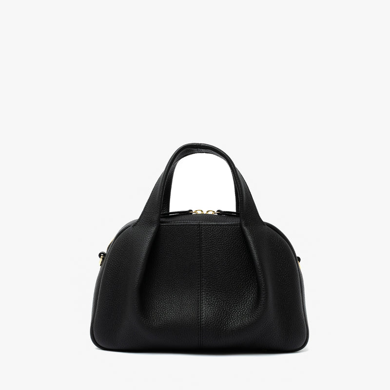 STOW London's Mini Bowling bag in Black pebbled leather featuring a pleated front panel and gold-coated stainless steel hardware on a light grey background
