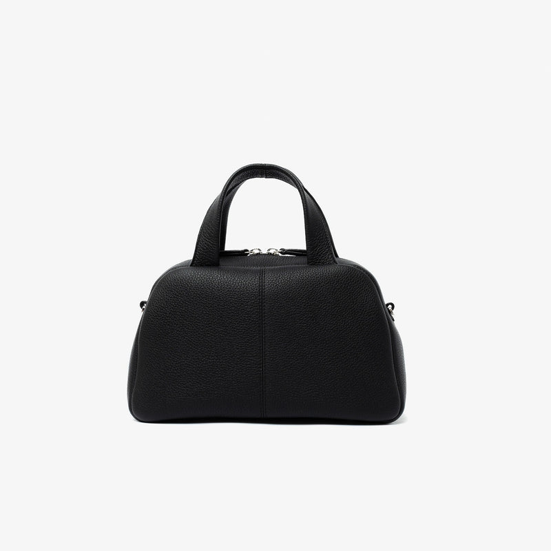 Back panel of STOW London's Mini Bowling bag in Black pebbled leather featuring silver stainless steel hardware and four feet on the base on a light grey background