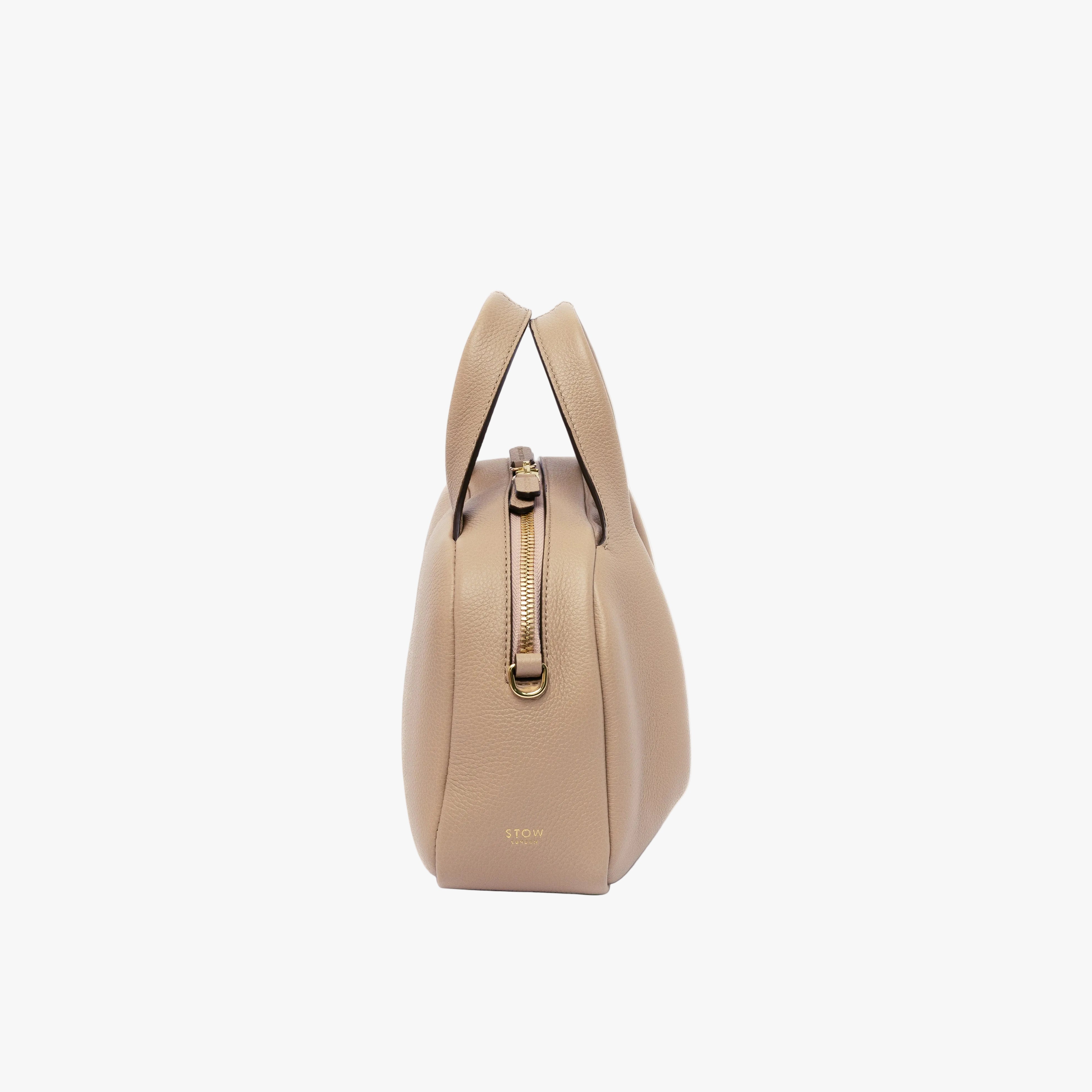 Side view of STOW London's Mini Bowling in Camel pebbled leather featuring gold-coated stainless steel hardware on a light grey background