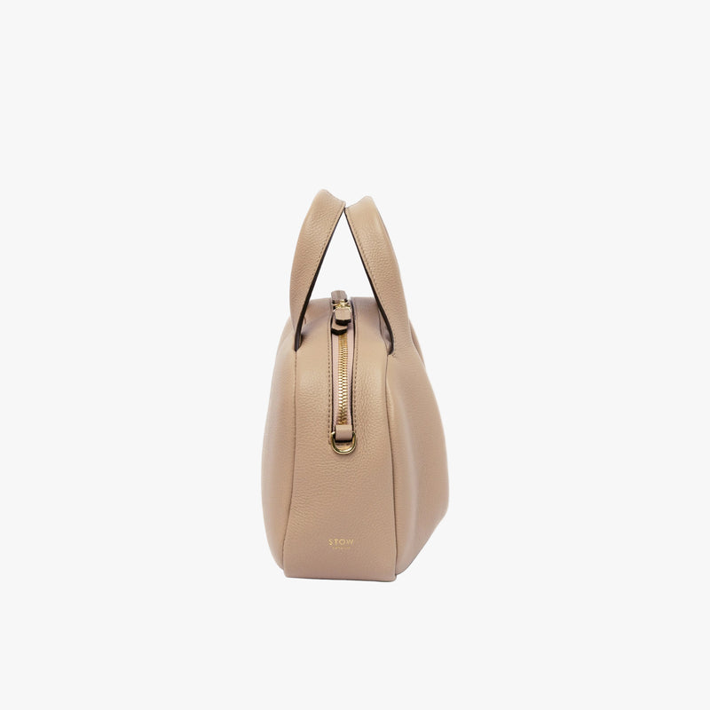 Side view of STOW London's Mini Bowling in Camel pebbled leather featuring gold-coated stainless steel hardware on a light grey background