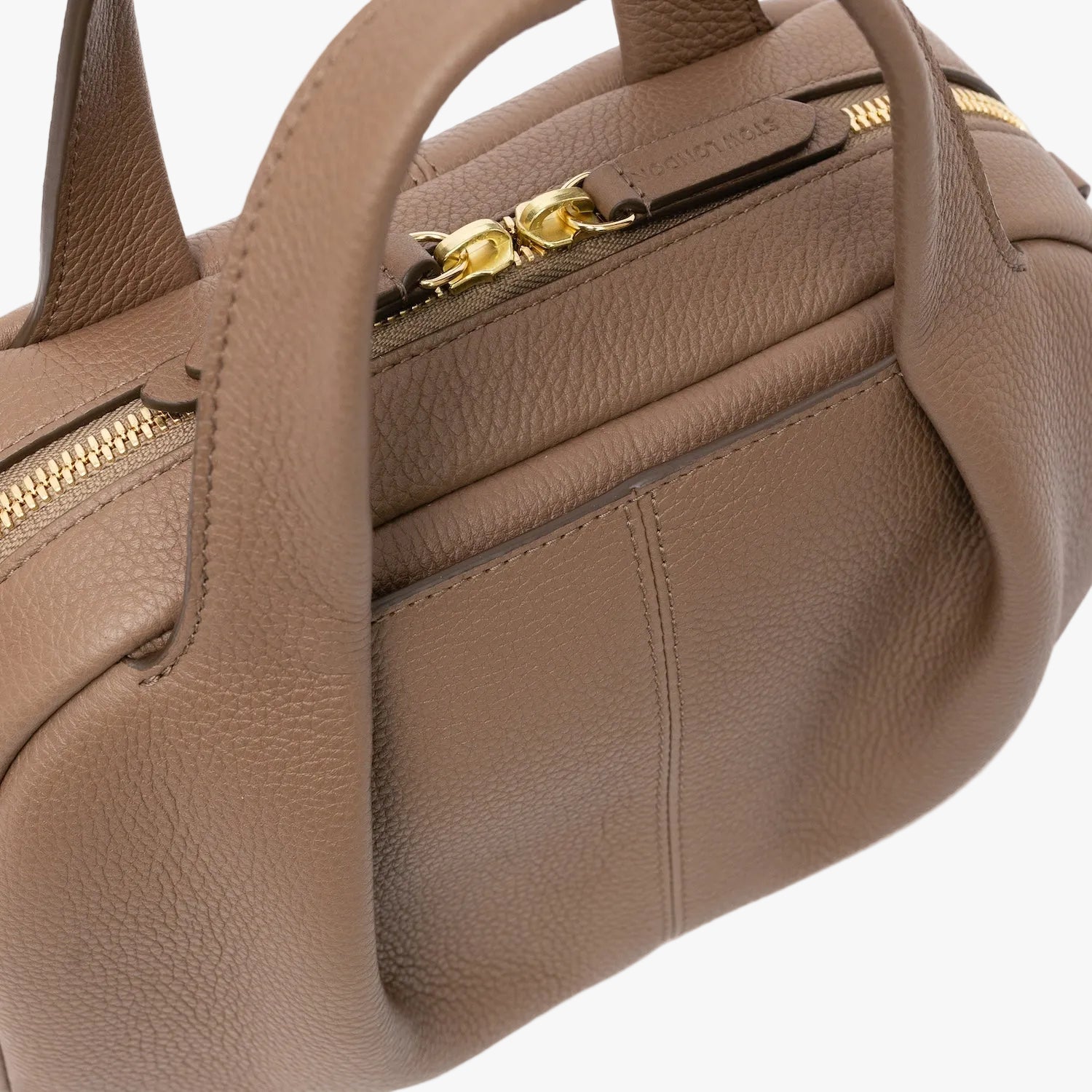 Close up of STOW London's Mini Bowling in Mocha pebbled leather featuring a pleated front panel and gold-coated stainless steel hardware on a light grey background 