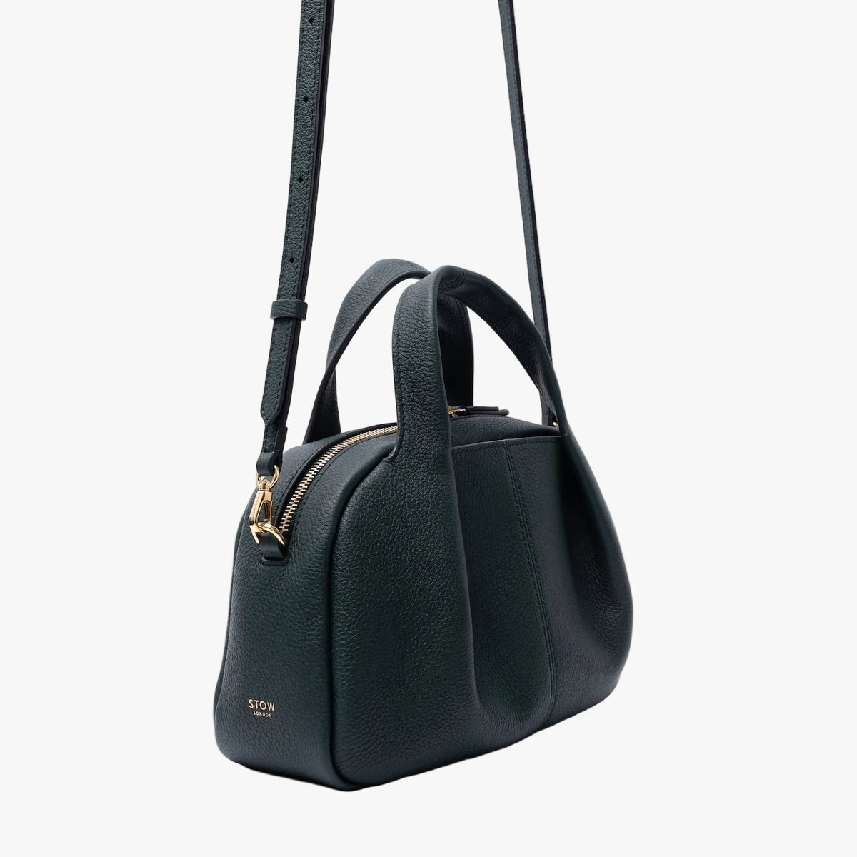 Off-axis view of STOW London's Mini Bowling in New Forest pebbled leather on a light grey background featuring gold-coated stainless steel hardware and the detachable crossbody strap