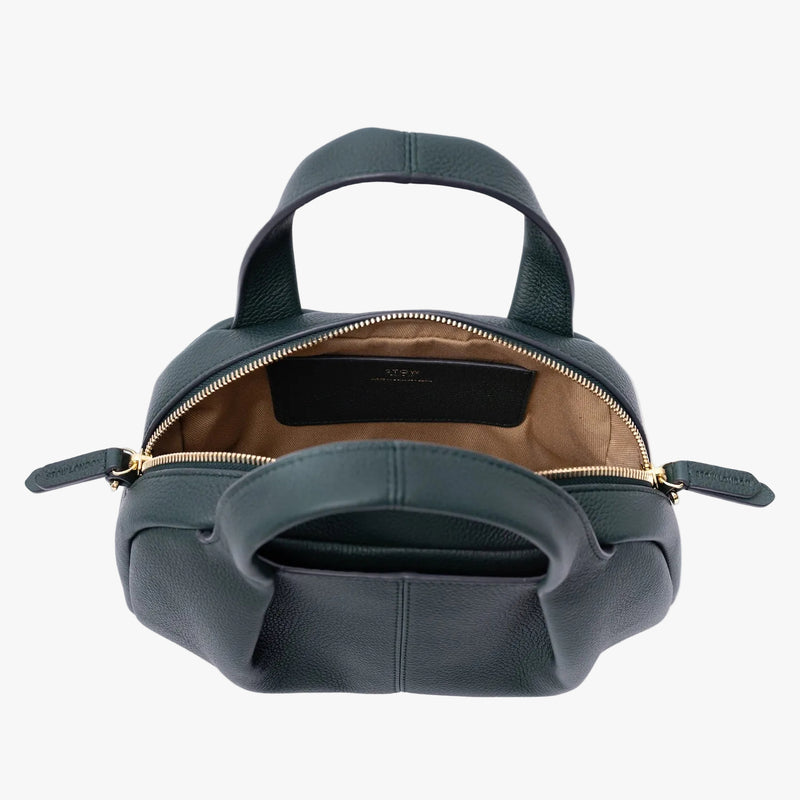 Top view of STOW London's Mini Bowling in New Forest pebbled leather on a light grey background with the zipper open showing the cotton interior lining and leather slip pocket