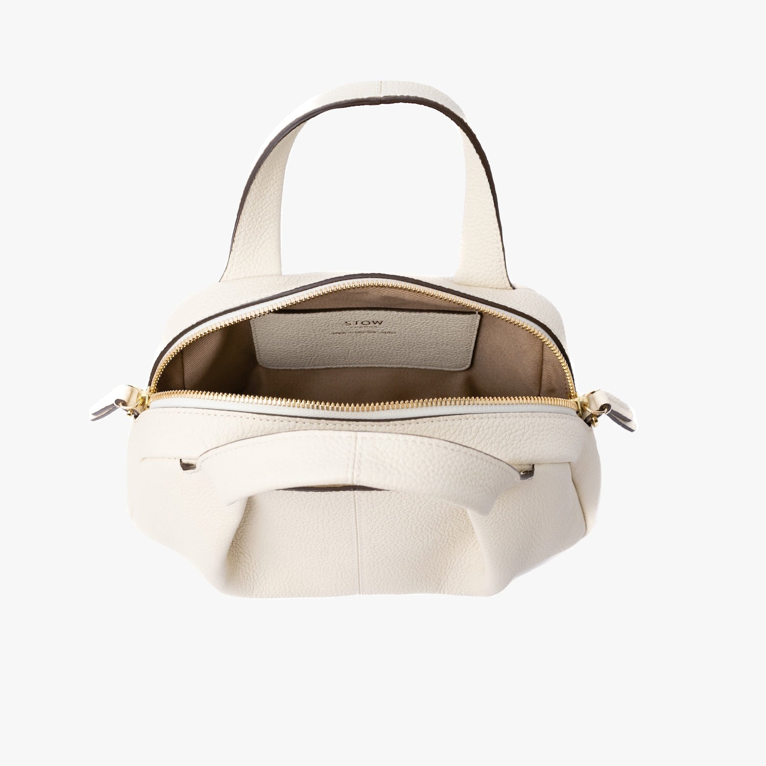 STOW London's Mini Bowling bag in Spring Moon pebbled leather with zip open showing cotton interior lining and leather slip pocket featuring gold-coated stainless steel hardware on a light grey background