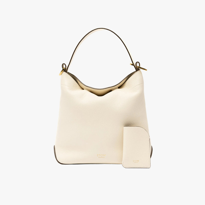 STOW London's Mini Cardholder in Spring Moon pebbled leather with the matching Midi Curve bag on a light grey background featuring a small gold embossed logo on the front bottom of both pieces