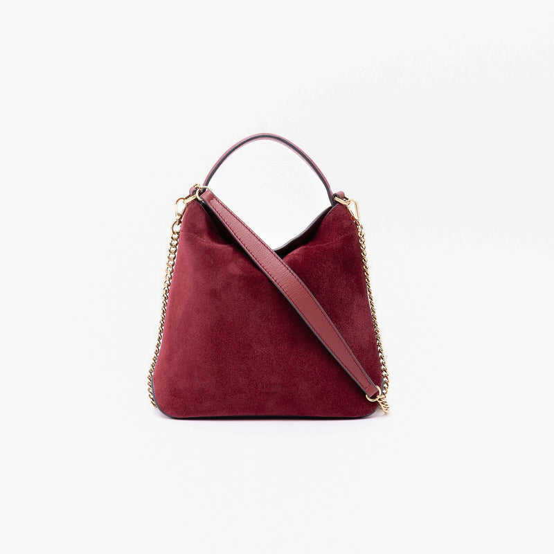 Stow London's Mini Curve in Burgundy suede leather and detachable gold chain crossbody strap styled as a flap bag on a light grey background 