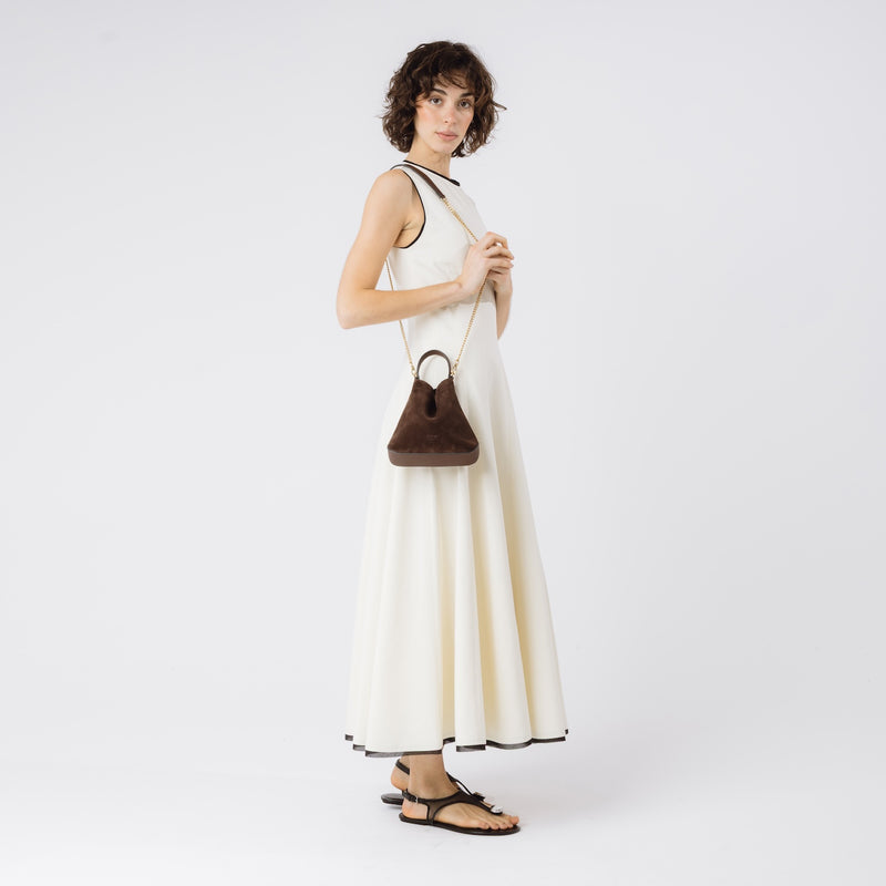 Model wearing STOW London's Mini Curve in Chocolate suede leather on her shoulder featuring gold-coated stainless steel hardware