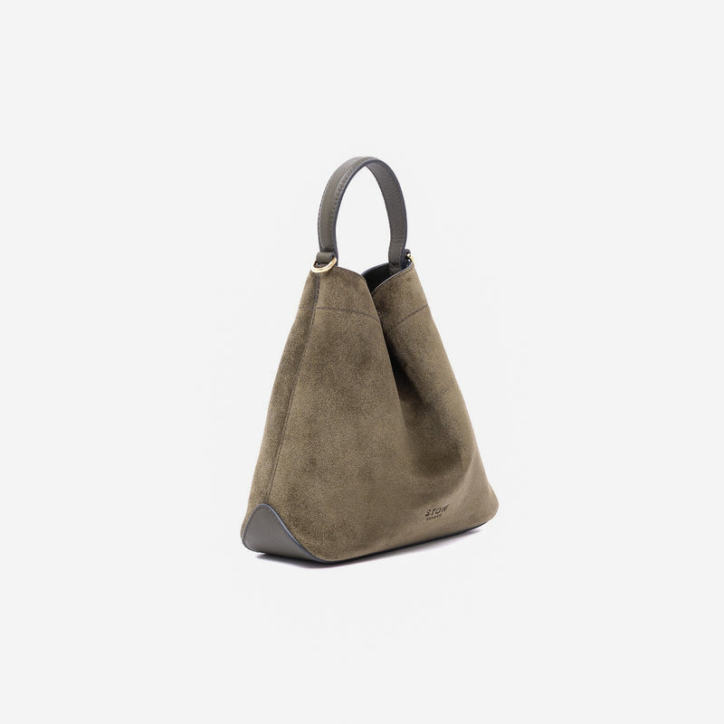 Off-axis view of Stow London's Mini Curve in Dark Green suede leather featuring gold-coated stainless steel hardware on a light grey background 