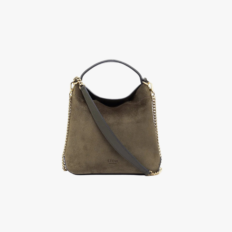 STOW London's Mini Curve in Dark Green suede leather featuring gold-coated stainless steel hardware and chain on a light grey background