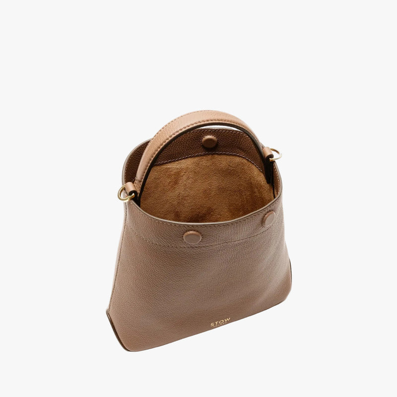Overhead shot of STOW London's Mini Curve in Mocha pebbled leather with magnets open showing suede interior featuring gold-coated stainless steel hardware on a light grey background