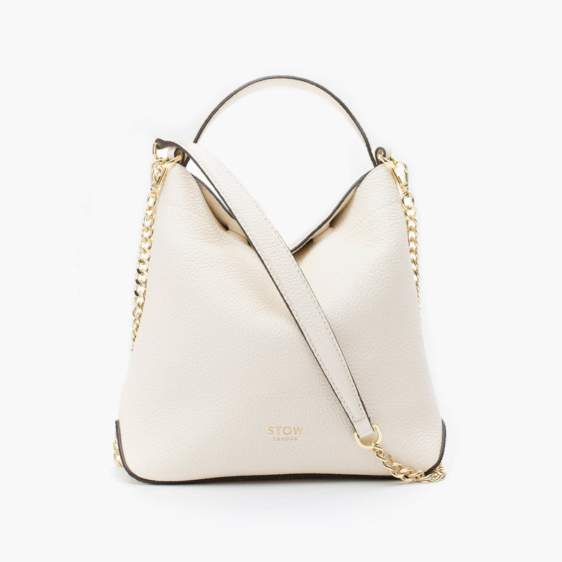 STOW London's Mini Curve in Spring Moon pebbled leather and detachable gold chain crossbody strap on a light grey background 