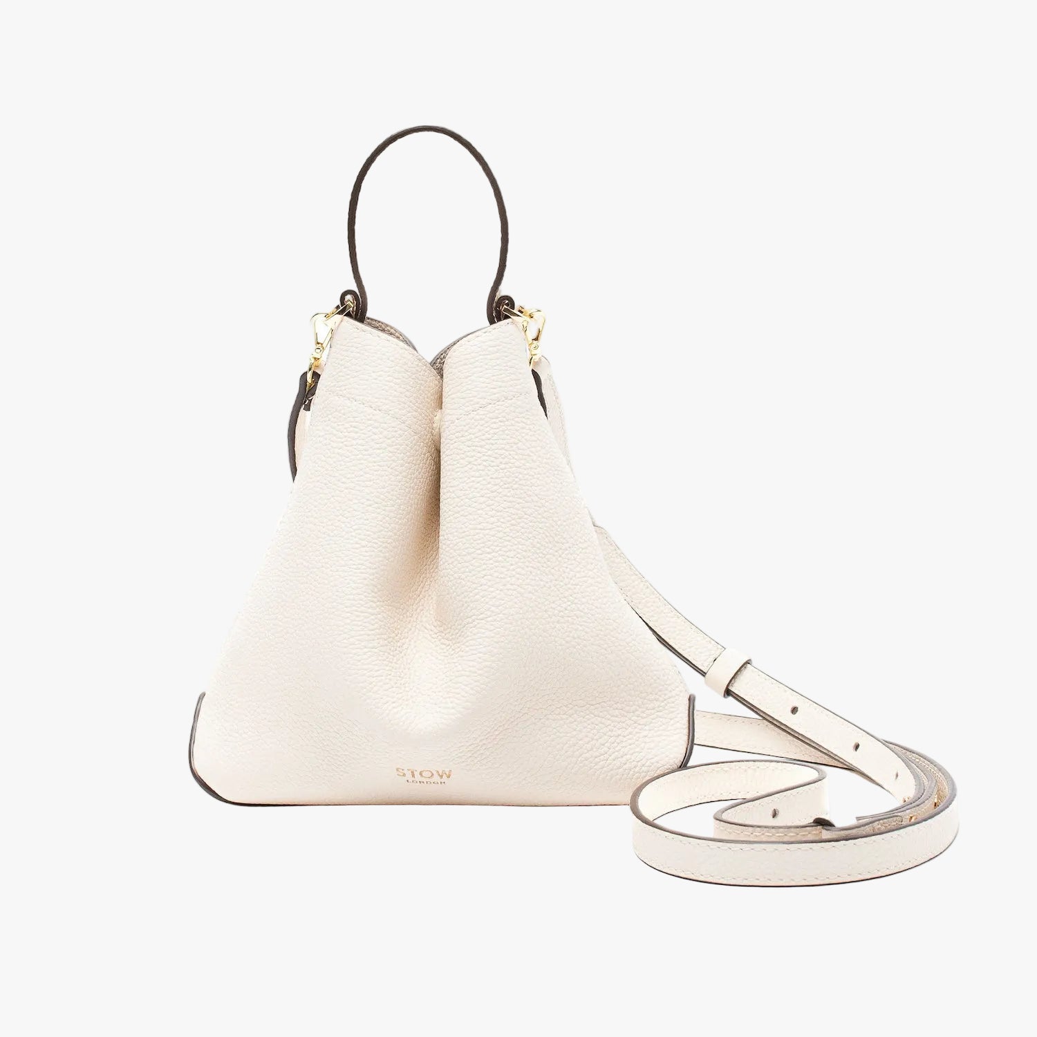 STOW London's Mini Curve in Spring Moon pebbled leather and detachable leather crossbody strap on a light grey background 