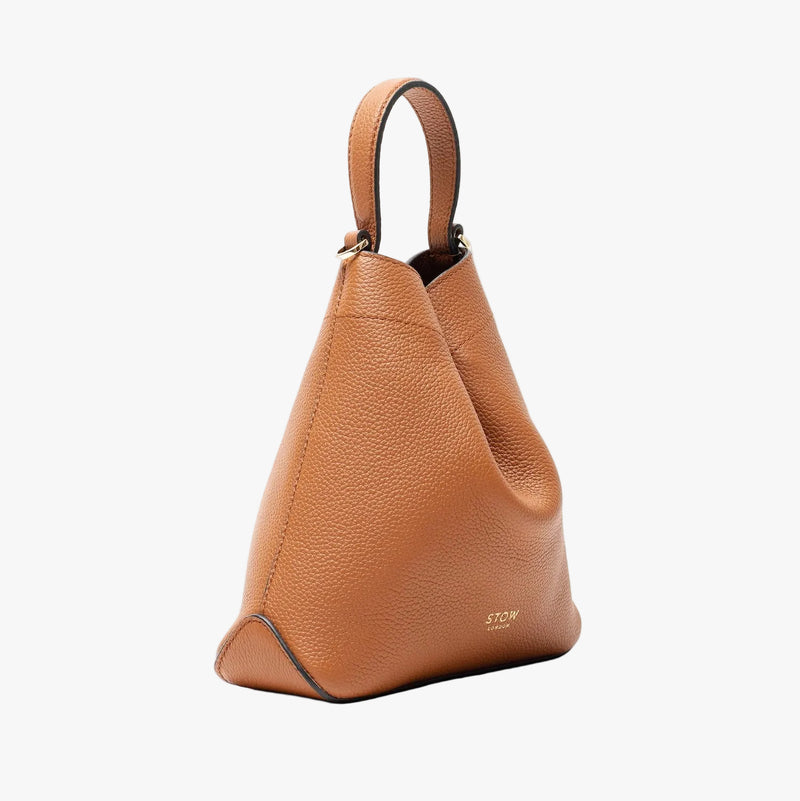Off-axis view of STOW London's Mini Curve in Earth tan pebbled leather on a light grey background 