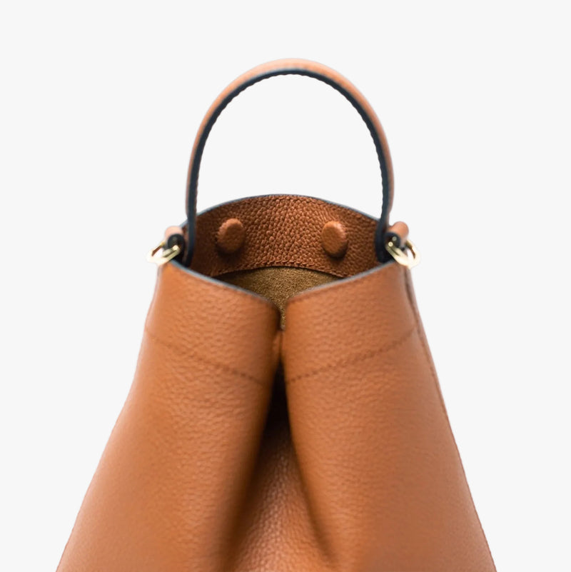 Close up of the top handle and discreet magnets on STOW London's Mini Curve in Earth tan pebbled leather on a light grey background 