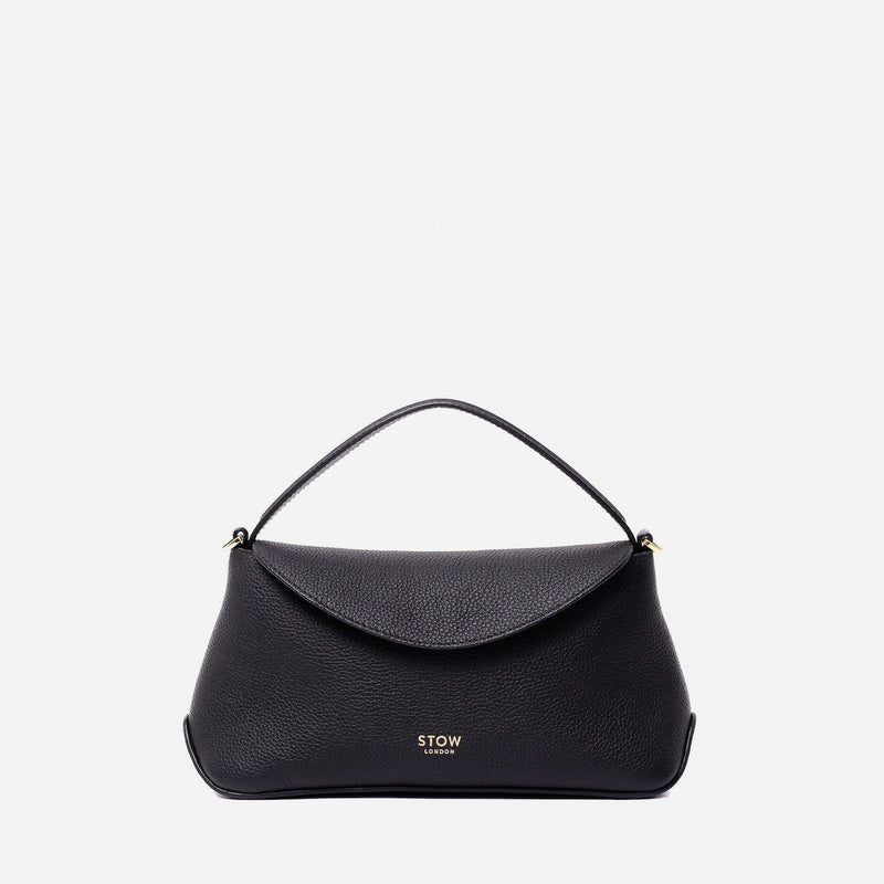 STOW London's Mini East West in Black pebbled leather featuring gold-coated stainless steel hardware on a light grey background