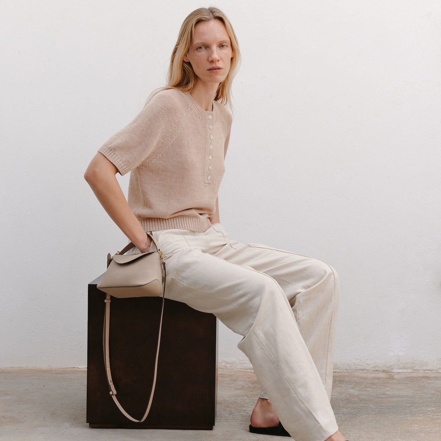 Model sat with STOW London's Mini East West in Camel pebbled leather featuring gold-coated stainless steel hardware