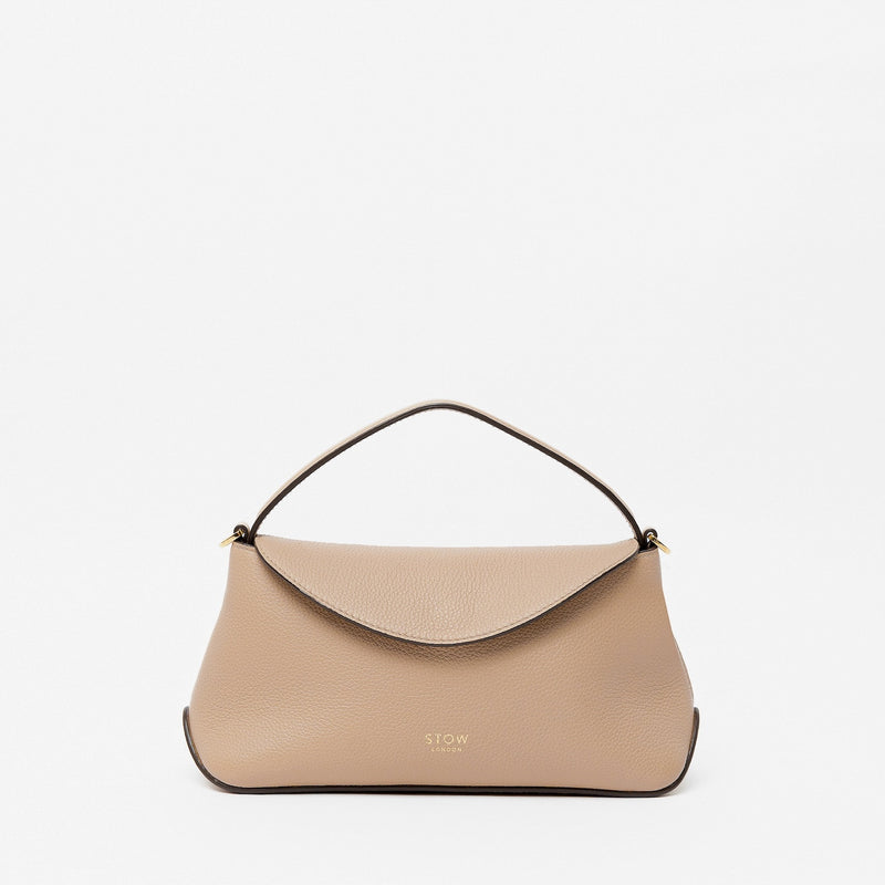 STOW London's Mini East West in Camel pebbled leather featuring gold-coated stainless steel hardware on a light grey background