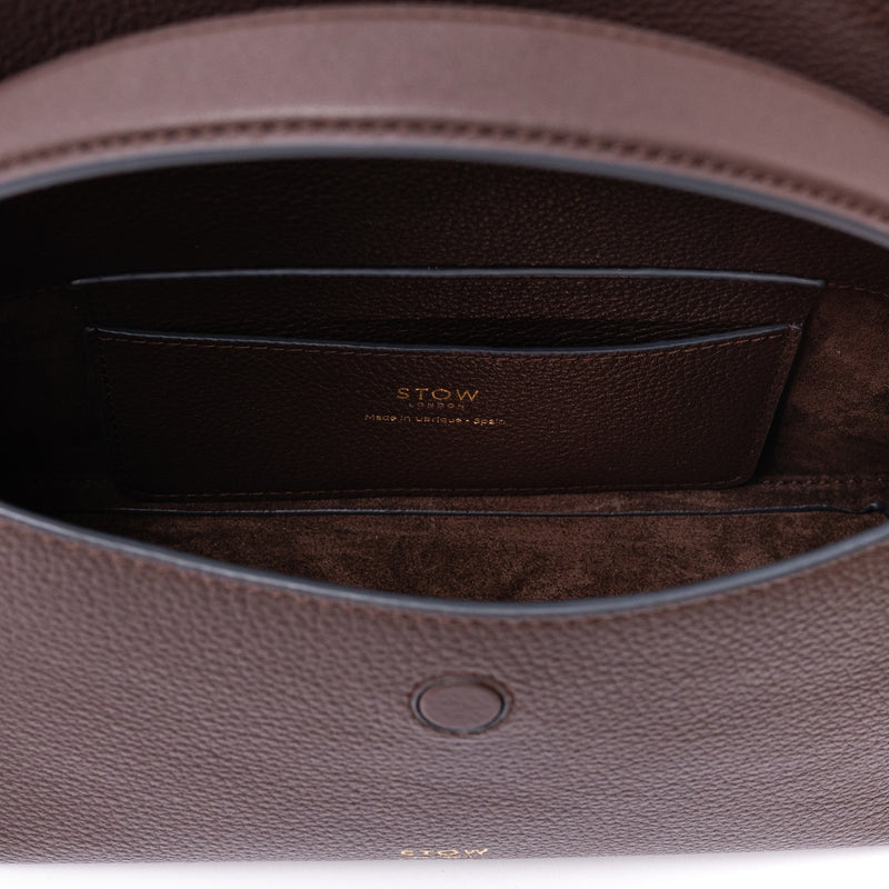 Close up of the interior of STOW London's Mini East West in Espresso pebbled leather on a light grey background featuring a chocolate suede lining and leather slip pocket