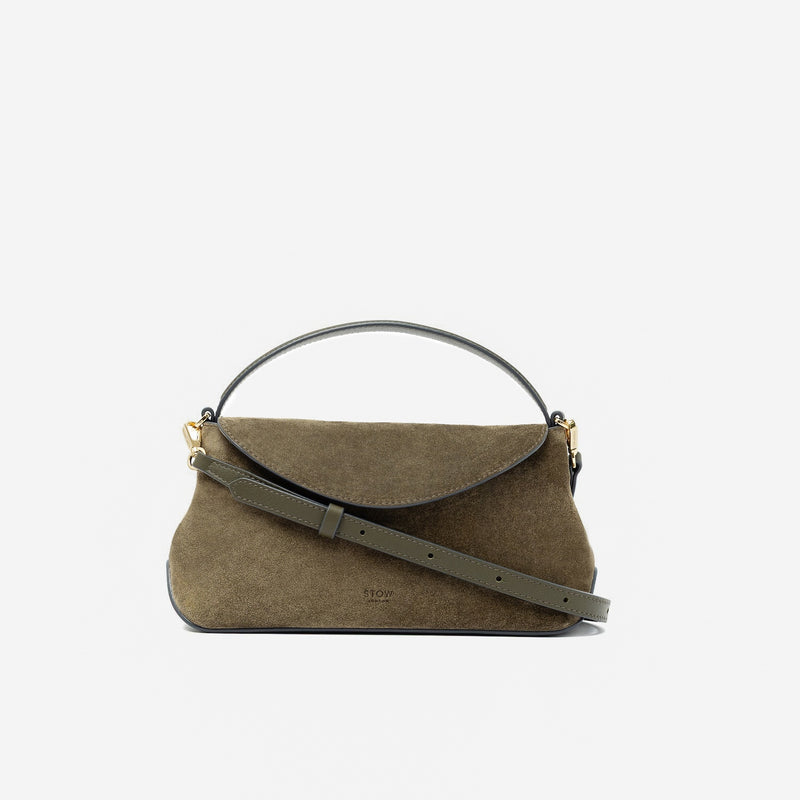 STOW London's Mini East West in Dark Green suede leather and detachable crossbody strap featuring gold-coated stainless steel hardware on a light grey background