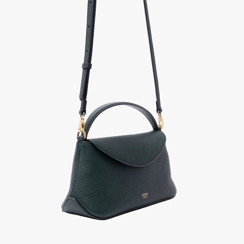 Off-axis view of STOW London's Mini East West in New Forest pebbled leather on a light grey background featuring gold-coated stainless steel hardware and the detachable crossbody strap