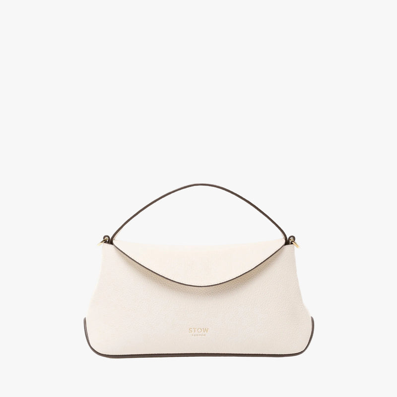STOW London's Mini East West in Spring Moon pebbled leather featuring gold-coated stainless steel hardware on a light grey background