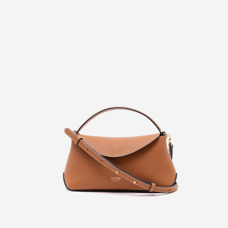 STOW London's Mini East West in Earth Tan pebbled leather and detachable crossbody strap featuring gold-coated stainless steel hardware on a light grey background
