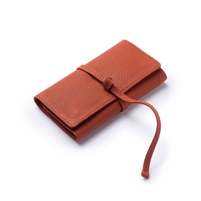 STOW Mini Jewellery Roll in Clay Orange pebbled leather closed with leather tie.