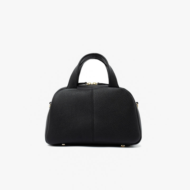 Back panel of STOW London's Mini Bowling bag in Black pebbled leather featuring gold-coated stainless steel hardware and four feet on the base on a light grey background