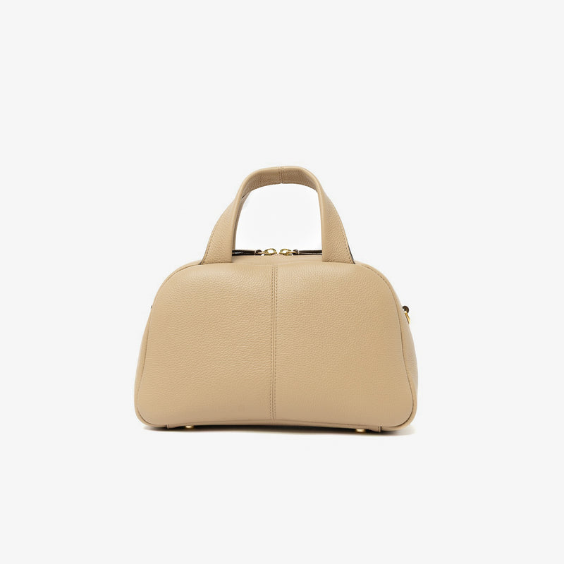 Back panel of STOW London's Mini Bowling bag in Camel pebbled leather featuring gold-coated stainless steel hardware and four feet on the base on a light grey background