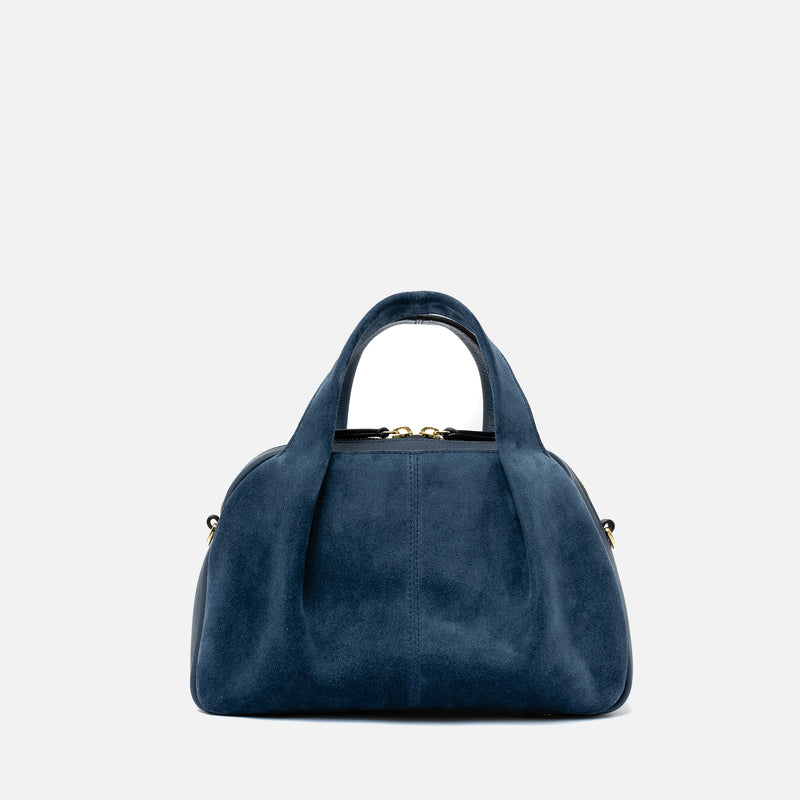 STOW London's Mini Bowling bag in Navy suede and smooth leather featuring a pleated front panel and gold-coated stainless steel hardware on a light grey background