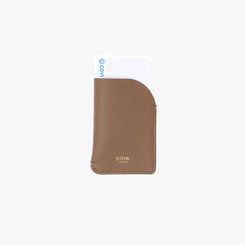 STOW London's Mini Cardholder in Mocha pebbled leather on a light grey background featuring a card sticking out the top and a small gold embossed logo on the front bottom