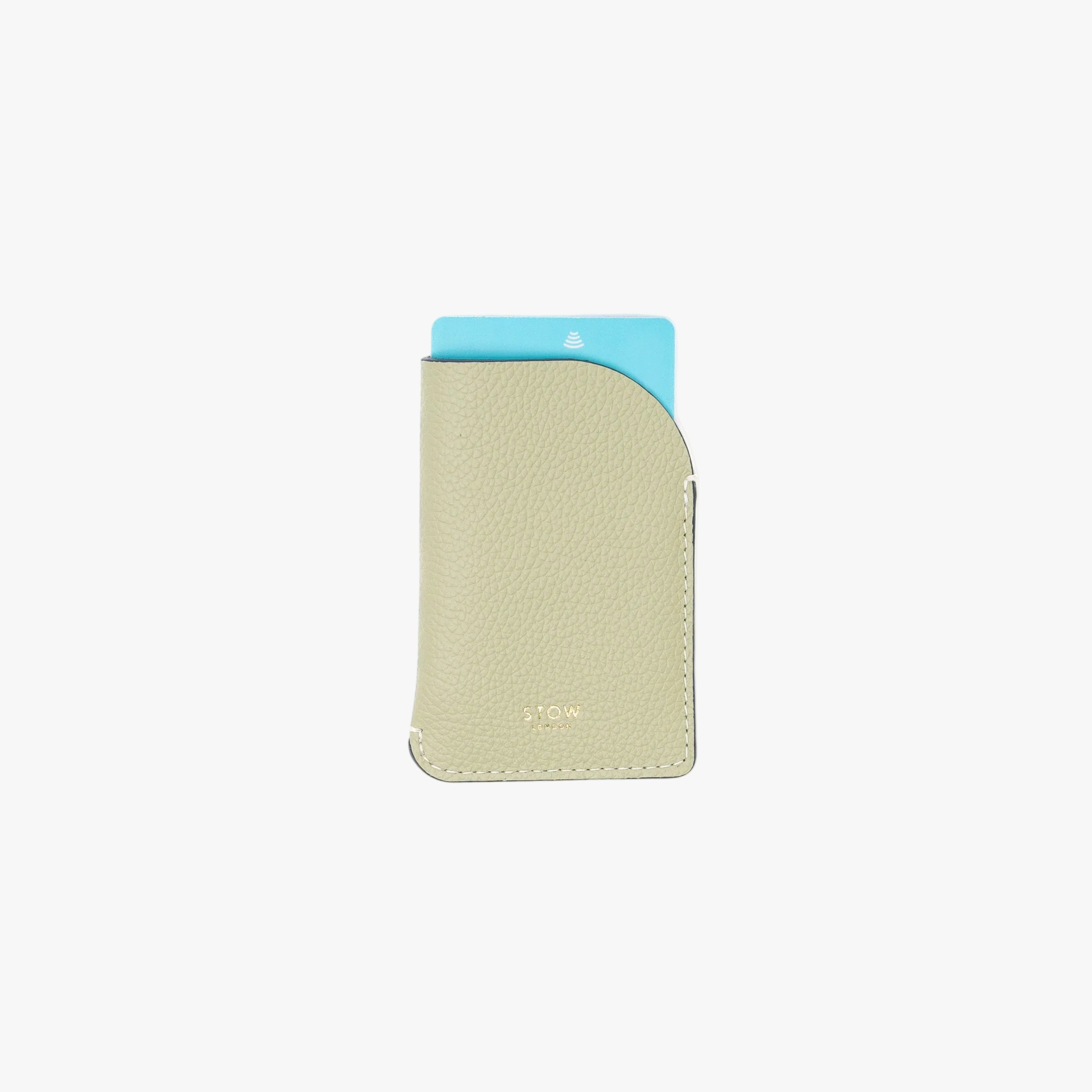 STOW London's Mini Cardholder in Pale Green pebbled leather on a light grey background featuring a card sticking out the top and a small gold embossed logo on the front bottom