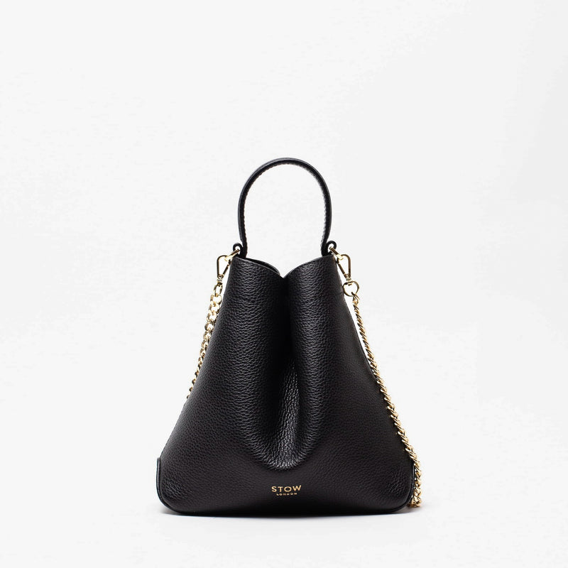 STOW London's Mini Curve in Black pebbled leather and detachable gold chain crossbody strap on a light grey background 