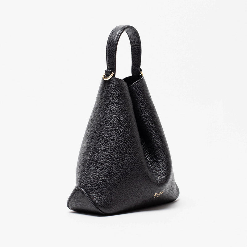 Off-axis view of STOW London's Mini Curve in Black pebbled leather featuring gold details on a light grey background 