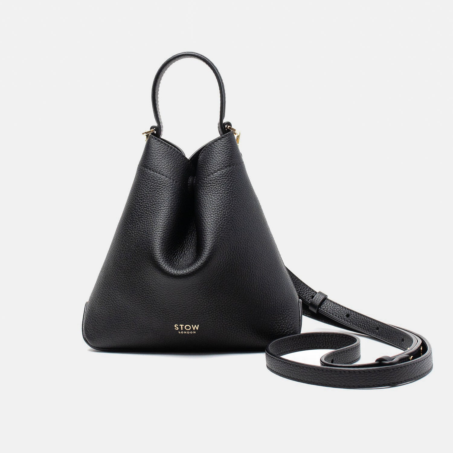 STOW London's Mini Curve in Black pebbled leather and detachable leather crossbody strap on a light grey background 