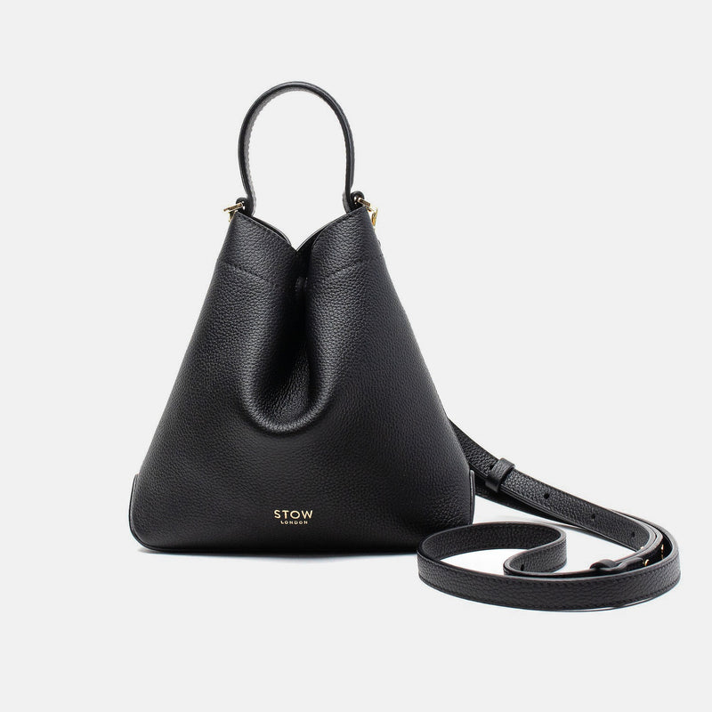 STOW London's Mini Curve in Black pebbled leather and detachable leather crossbody strap on a light grey background 