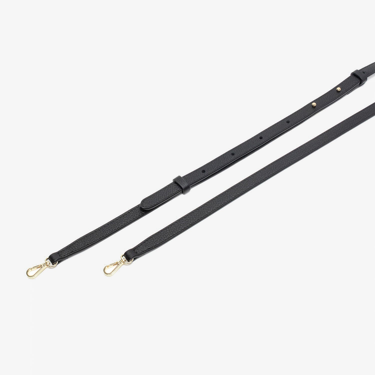 Close up of the detachable leather crossbody strap for STOW London's Mini Curve in Black pebbled leather on a light grey background 